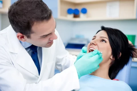 Dentist examining a female patient's teeth during a dental checkup in a clinic.